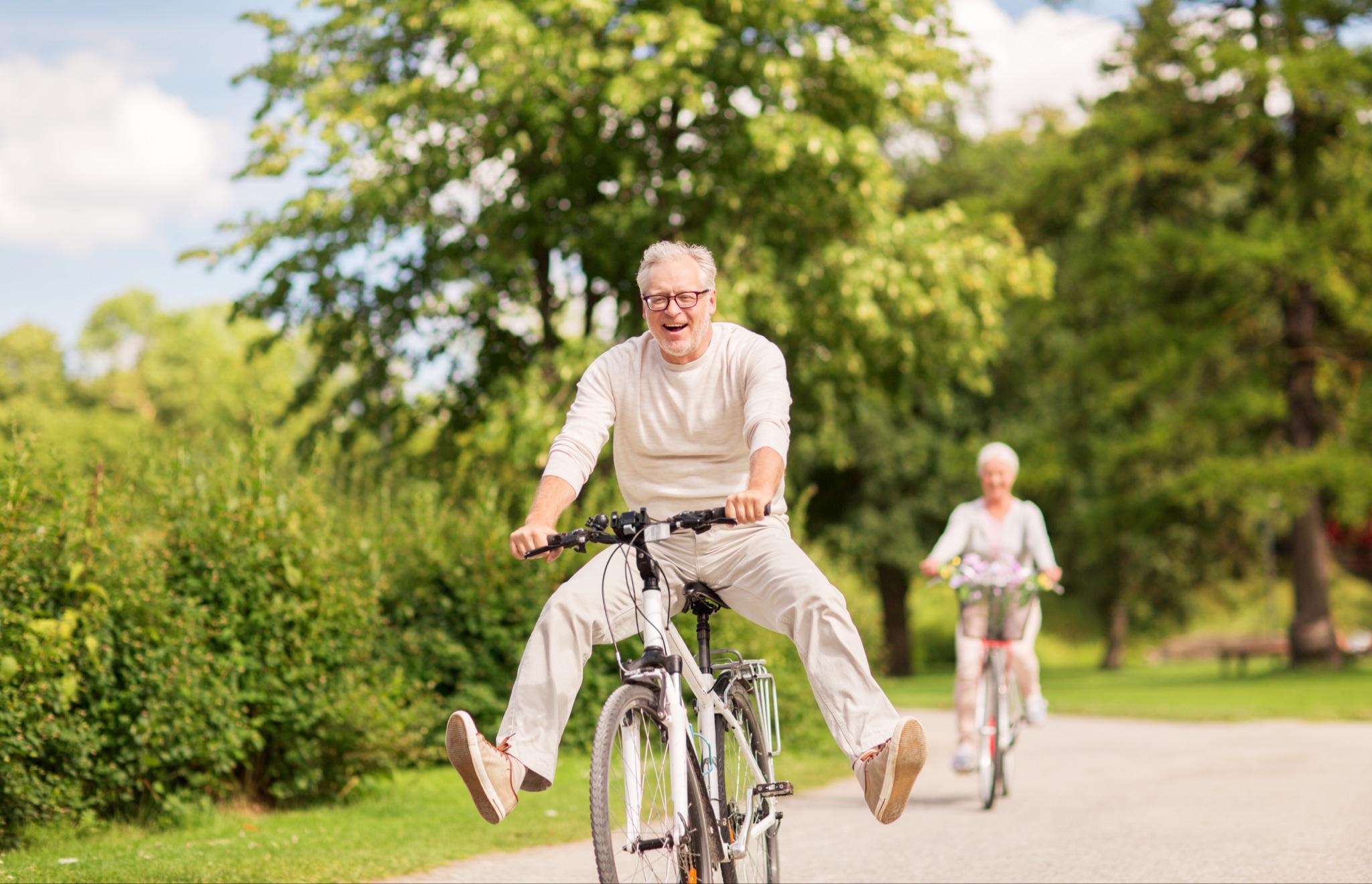 Elderly couple enjoying a bicycle ride through the trees.