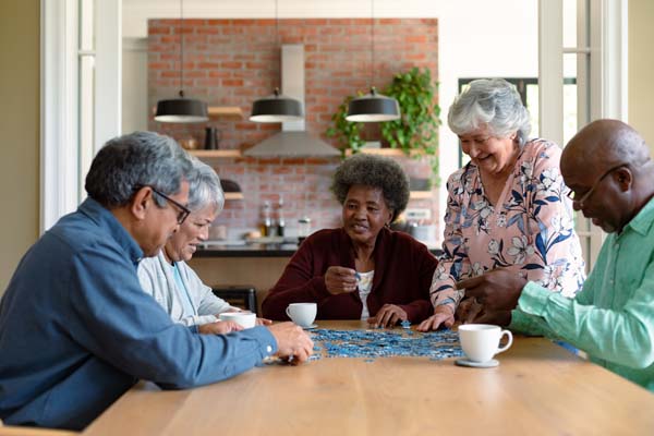 Group of seniors socializing with a puzzle and coffee.
