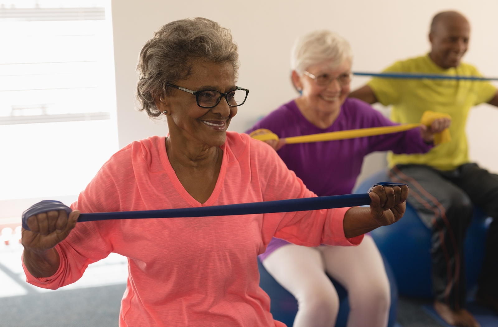 Three senior citizens practicing muscle building exercises