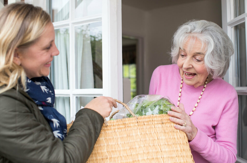 Woman handing groceries to mature woman