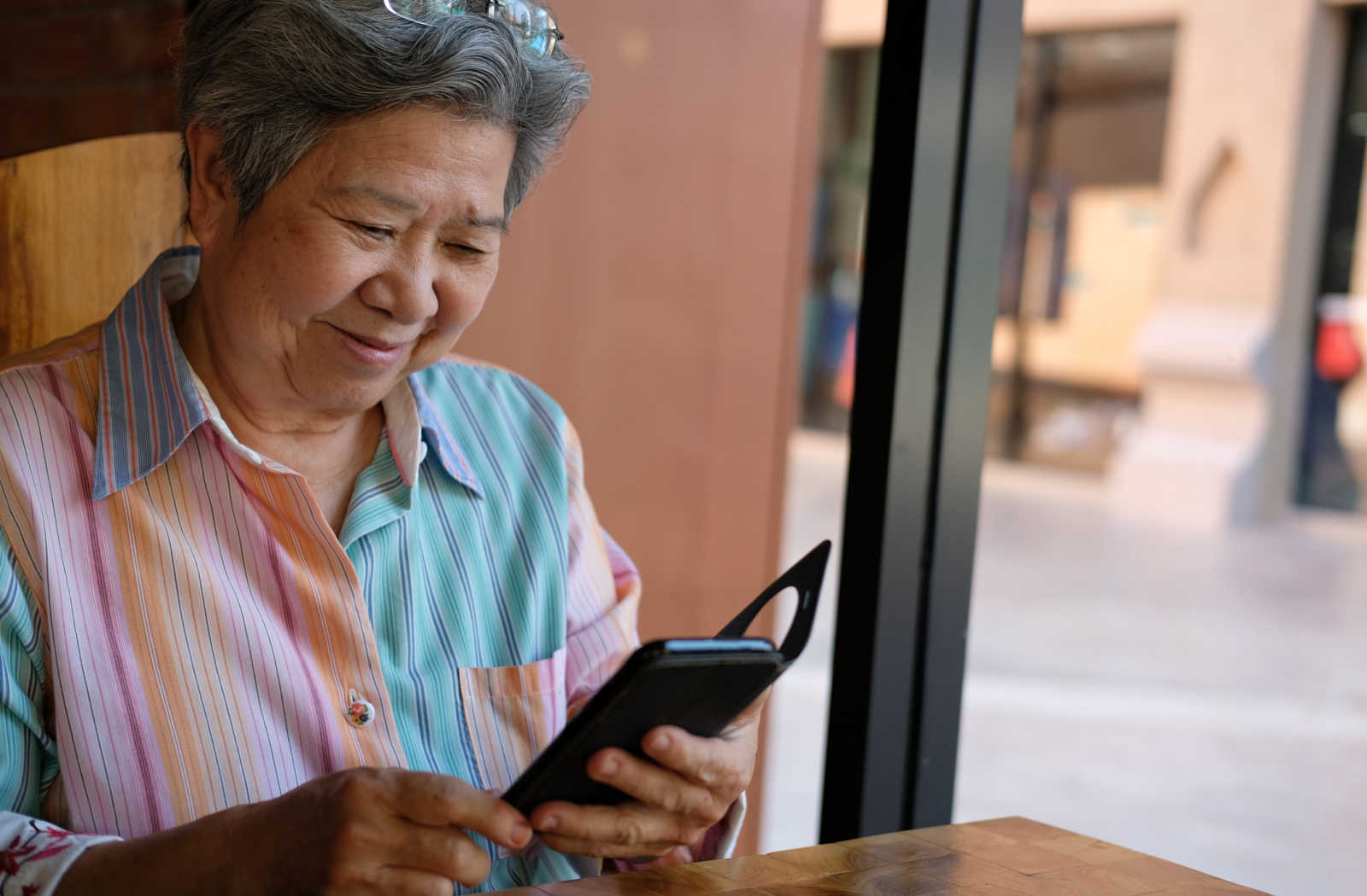 A senior woman holding a smartphone and looking at the screen.